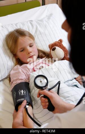 L'infermiera la misura della pressione del sangue di un paziente giovane, 7 anni, in ospedale Foto Stock