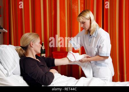 L'infermiera di lavaggio di un paziente in un letto di ospedale Foto Stock