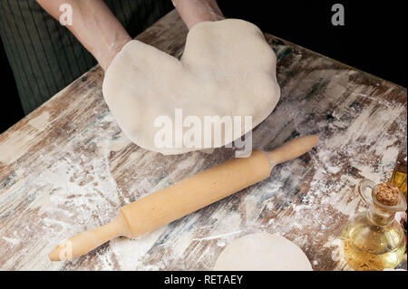 Le mani delle donne di stendere la pasta per pizza fatta in casa Foto Stock