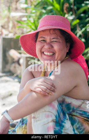 Bella donna filippina indossando variopinti hat e sorrisi vestito come lei si rilassa sulla lama Isola, Hong Kong, noto per un rilassato e rilassato stile di vita. Foto Stock