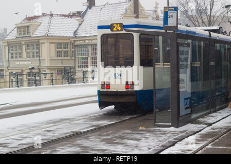 Amsterdam, Paesi Bassi - 22 Gennaio 2019: GVB tram veloce a Amsterdam centrale nella neve vista da sopra Foto Stock