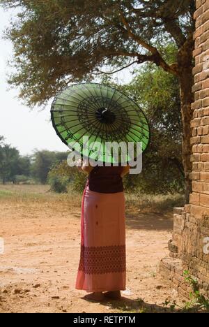 Vista posteriore di una giovane donna birmana con un ombrellone verde, Bagan, Myanmar Foto Stock