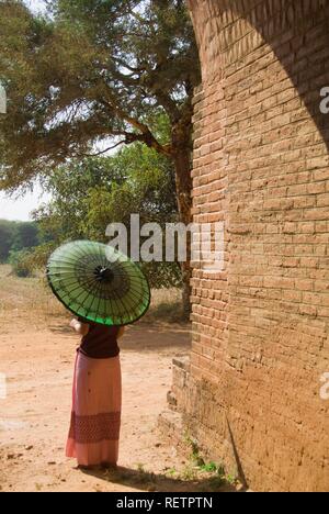 Vista posteriore di una giovane donna birmana con un ombrellone verde, Bagan, Myanmar Foto Stock