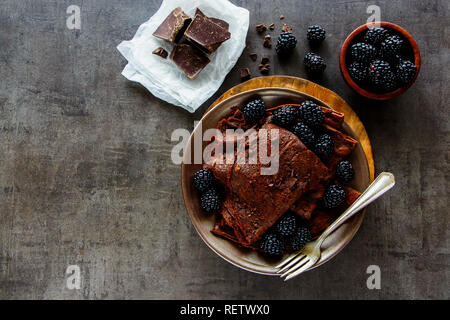 Flat-lay di crepes al cioccolato. Frittelle sottili, barre di cioccolato e fresche more Foto Stock
