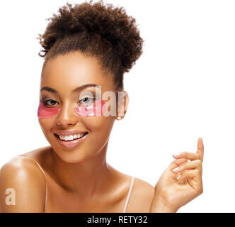 Sorridente bella donna con patch di rosa sul suo viso. Ritratto di African American donna con una pelle perfetta su sfondo bianco. Cura della Pelle concept Foto Stock