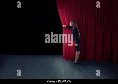 Donna aprire tende rosse del palcoscenico teatrale Foto Stock