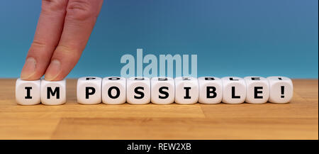 Dadi forma la parola 'impossibile' mentre due dita spingere le lettere "IM" di distanza al fine di modificare la parola "possibile". Foto Stock