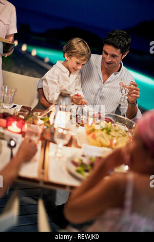 Famiglia gustando una cena all'aperto sul loro retro deck. Foto Stock