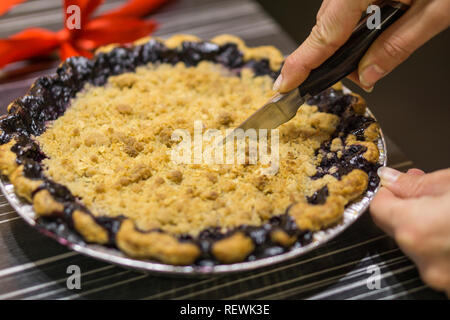 Bello stile americano torta ai mirtilli, mani umane a taglio in essa con il coltello Foto Stock