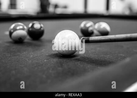 La palla cue sta per essere colpita su un tavolo da biliardo in bianco e nero Foto Stock