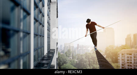 Ropewalker in black hat corda a piedi in alto nel cielo . I supporti misti Foto Stock