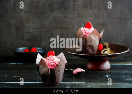 Tortine. Tortini di glassa decorata con lampone e rosa di crema di formaggio Foto Stock