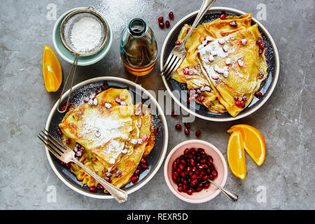 Crepes dolci e rabboccato con melograno e zucchero. Thin pancake, frutta e sciroppo d'acero flat-lay Foto Stock