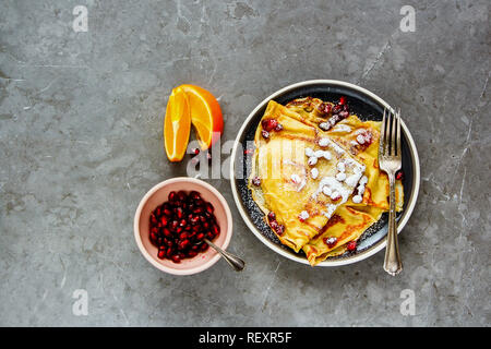 Crepes dolci e rabboccato con melograno e lo zucchero sulla piastra piana. laici In casa frittelle sottili e frutta Foto Stock