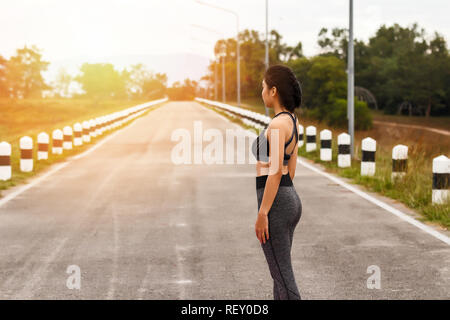 Asian sport donna in sportwear permanente sulla strada. Donna Fitness riposo dopo la sessione di allenamento. Foto Stock