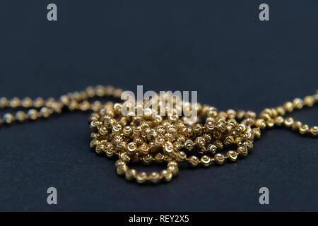Collana in oro isolati su sfondo nero, macro closeup mostra giallo golden maglie di catena dettaglio Foto Stock