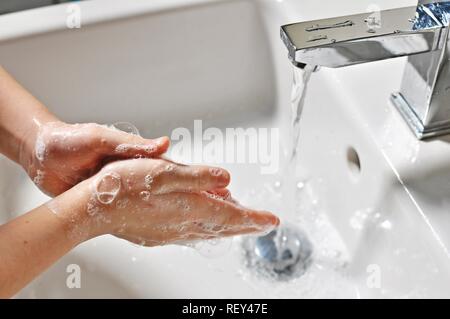 Bianco ragazza caucasica (bambino, kid) lavando le mani con sapone al di sopra del lavabo Foto Stock