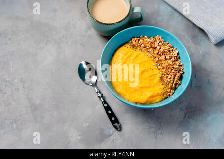 Vista superiore del frullato giallo ciotola con granola nella piastra di blu. Spazio di copia Foto Stock