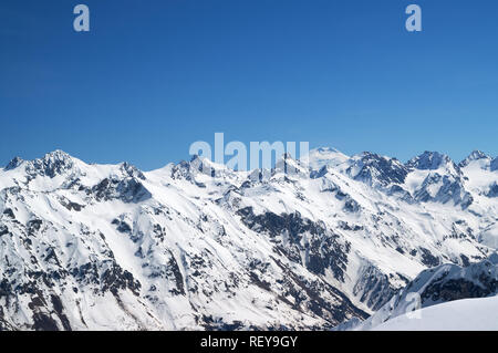 Montagne coperte di neve con il monte Elbrus in background. Vista dalla regione Dombay, Caucaso le montagne in inverno. Foto Stock