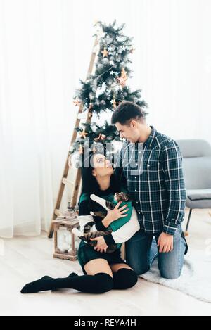 Matura in amore che giace nei pressi di albero di Natale e di giocare con il gatto di casa. Foto Stock