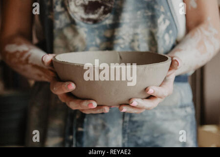 Ceramiche, argilla, arte ceramica concetto - Primo piano sulle mani del giovane maestro con la piastra grande da terra refrattaria Foto Stock