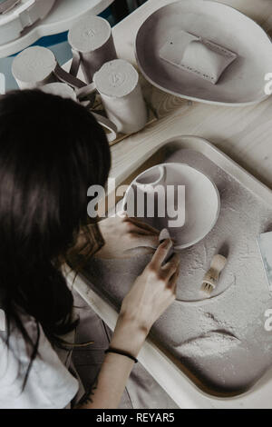 Donna fare ceramica. Close-up del processo di levigatura a piastra di argilla Foto Stock