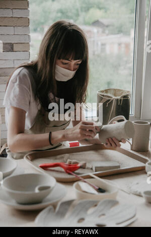 Donna fare ceramica. Close-up del processo di levigatura a piastra di argilla Foto Stock