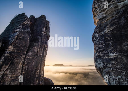 Il paesaggio del parco nazionale Sächsische Schweiz con formazioni rocciose e la nebbia nel fiume Elbe valley, visto dal ponte di Bastei di sunrise Foto Stock
