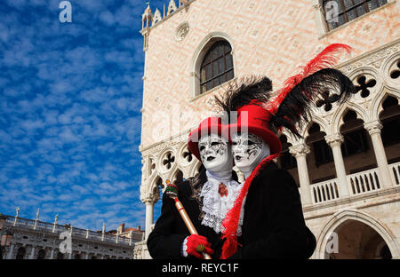 Carnevale a Venezia. Due carnevale veneziano maschere con il famoso Palazzo del Doge e le nuvole in background Foto Stock