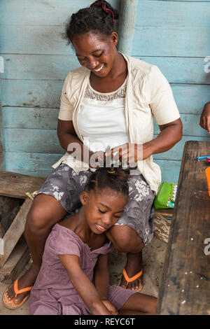 Andavadoaka, Madagascar - Gennaio 13th, 2019: Ritratto di un locale donna malgascia rendendo trecce per sua figlia in Andavadoaka, Madagascar. Foto Stock