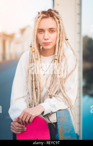 Giovane donna con skate ritratto sul ponte Foto Stock