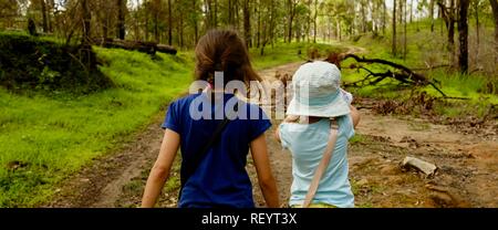 Due bambini a piedi lungo una trazione a quattro ruote motrici via attraverso una foresta, Mia Mia la foresta di stato, Queensland, Australia Foto Stock