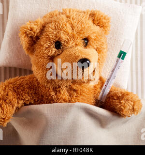 Health care concetto di orsacchiotto di peluche che giace nel letto con termometro Foto Stock