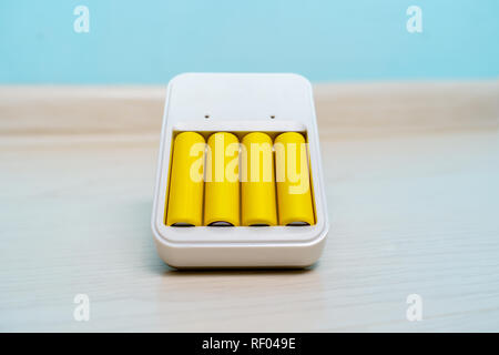 Foto di caricabatterie con due batterie vuoto su sfondo blu Foto Stock