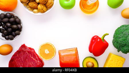 Foto sulla parte superiore di un pezzo di carne, pesce, formaggio, uova, verdure, frutta, olive, noci su sfondo bianco. Foto Stock