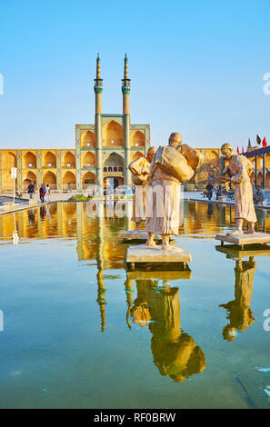 YAZD, IRAN - 18 ottobre 2017: Il bronzo composizione scultorea di portatori di acqua nella fontana di Amir Chakhmaq square con il vecchio Hosseinieh su backgrou Foto Stock