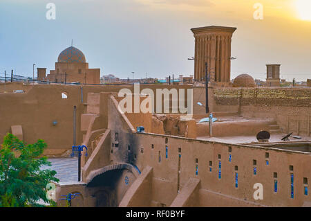 Il tramonto skyline del quartiere Fahadan con una vista su alte pareti di adobe, badgirs (torri del vento) e cupola stellare di Madraseh-e Kamalieh, Yazd, Iran. Foto Stock