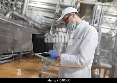 Un dipendente con un laptop nelle sue mani presso il caseificio Foto Stock