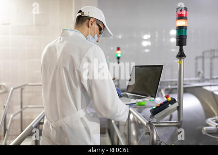 Un dipendente con un laptop nelle sue mani presso il caseificio Foto Stock