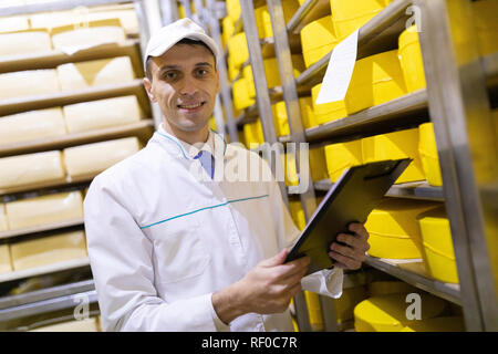 Ispettore rende note in foglio in corrispondenza del magazzino di formaggio Foto Stock