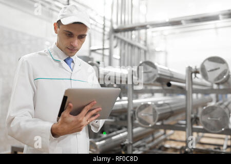 Il Tecnologo con una compressa nelle sue mani presso il caseificio Foto Stock