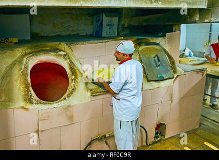 YAZD, IRAN - 18 ottobre 2017: il panettiere sta per mettere le materie flatbread alla terra forno tandoor, il 18 ottobre a Yazd Foto Stock