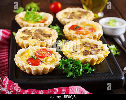 Funghi, cheddar, pomodori canapes su sfondo di legno. Mini torte. Delizioso antipasto, tapas, snack. Foto Stock
