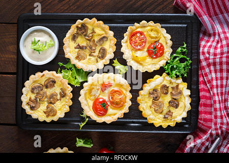 Funghi, cheddar, pomodori canapes su sfondo di legno. Mini torte. Delizioso antipasto, tapas, snack. Vista dall'alto. Lay piatto Foto Stock