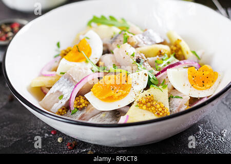 Tradizionale insalata di aringhe salate filetto, mele fresche, cipolla rossa e uova. Cibo Kosher. Cucina scandinava. Foto Stock