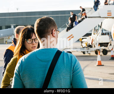 BASEL, Svizzera - Nov 11, 2018: uomo e donna che parlano nei pressi di EasyJet Airbus A320-214 OE-IJR piano su asfalto con passeggeri discendente dalla uscita anteriore su una luminosa giornata di sole Foto Stock