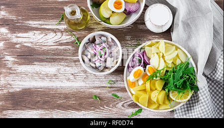 Tradizionale insalata di aringhe salate filetto, uova fresche Mele, cipolla rossa e patate. Cibo Kosher. Cucina scandinava. Vista dall'alto. Lay piatto Foto Stock