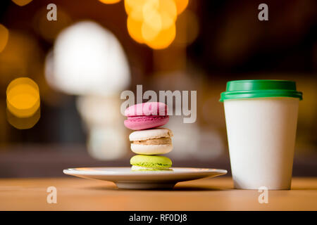 Amaretti colorati e una carta tazza da caffè per andare in cafe Foto Stock