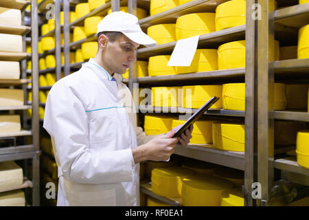 Ispettore rende note in foglio in corrispondenza del magazzino di formaggio Foto Stock