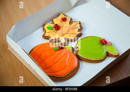 In casa di panpepato biscotti a forma di zucca di Halloween. Autunno foglie di acero sul vecchio sfondo di legno. Foto Stock